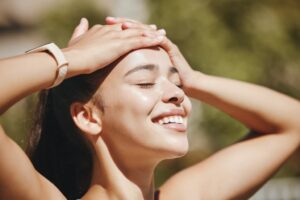 Happy woman with glowing, hydrated skin smiling outdoors, demonstrating the radiant complexion results achievable with regular HydraFacial treatment maintenance