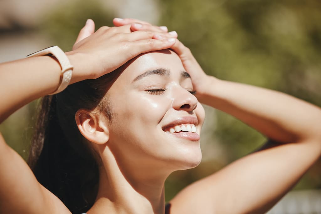 Happy woman with glowing, hydrated skin smiling outdoors, demonstrating the radiant complexion results achievable with regular HydraFacial treatment maintenance